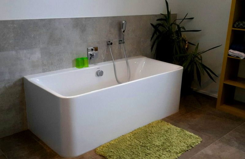 Moderne Badewanne mit grauer Fliesenwand