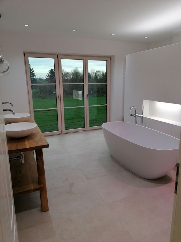 Modernes Bad mit freistehender Badewanne und Blick in den Garten