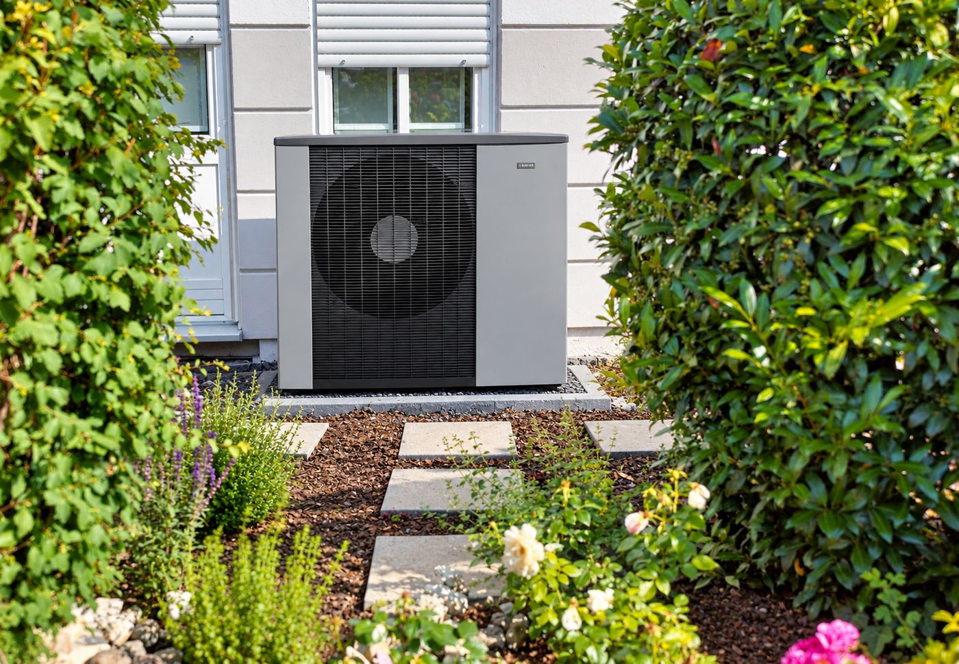 Luft-Wärmepumpe Außengerät an einer Hauswand im Garten